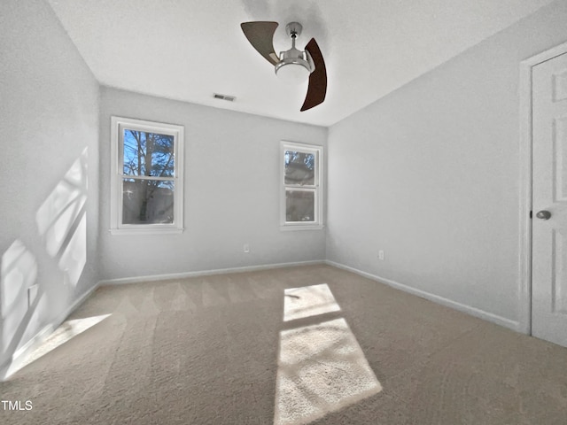 carpeted spare room featuring ceiling fan and plenty of natural light