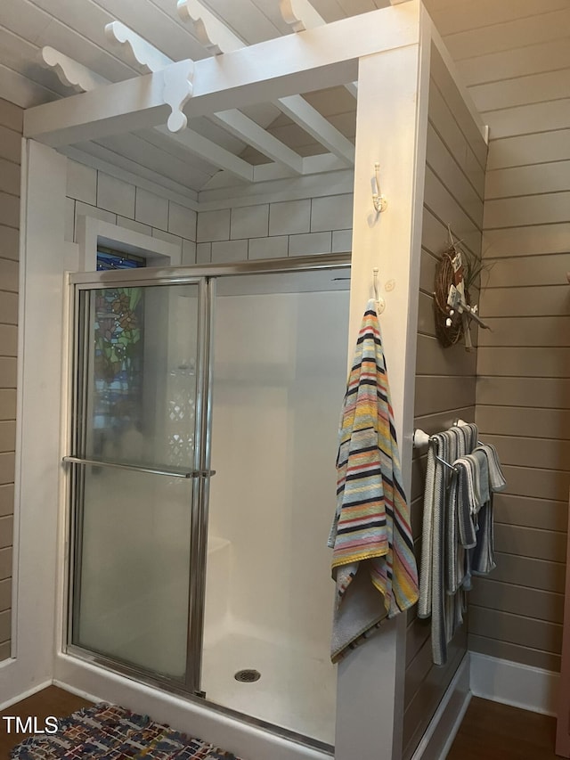 bathroom featuring wooden walls and walk in shower