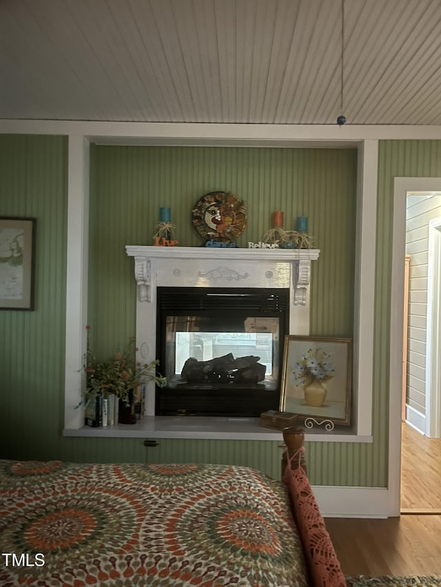 bedroom featuring a multi sided fireplace and hardwood / wood-style floors