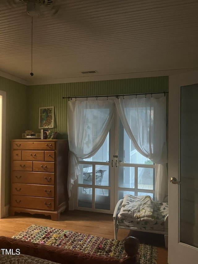 bedroom featuring french doors, ornamental molding, and wood-type flooring