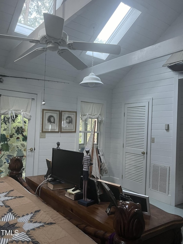 interior space featuring wooden walls, ceiling fan, vaulted ceiling with skylight, and hardwood / wood-style floors