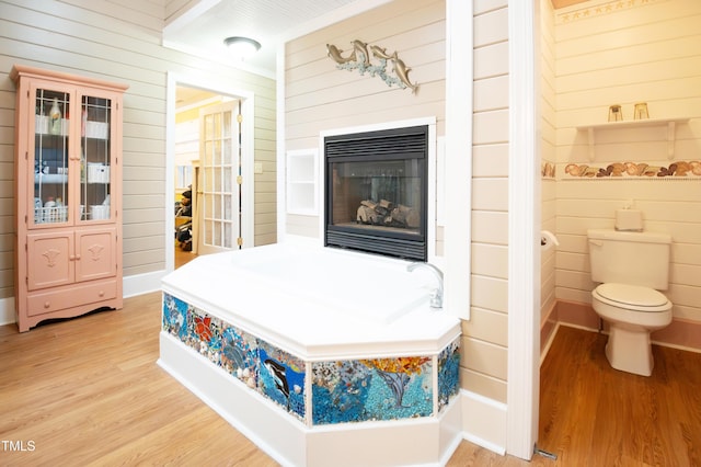 bedroom with ensuite bath, wooden walls, and light wood-type flooring