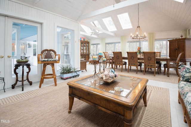 sunroom / solarium featuring a healthy amount of sunlight, vaulted ceiling with skylight, and a chandelier