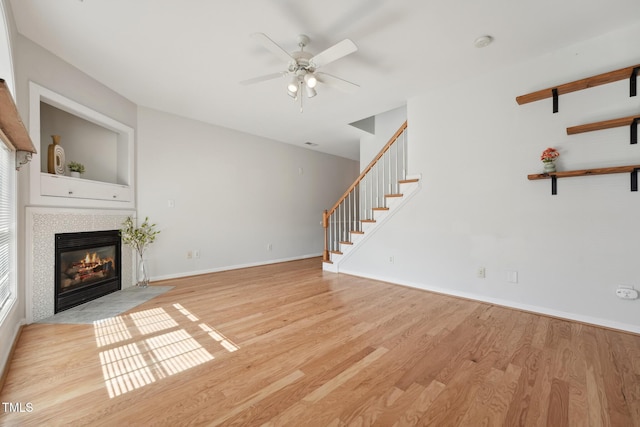 unfurnished living room featuring a fireplace, ceiling fan, and light wood-type flooring