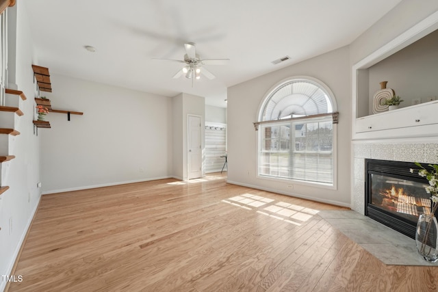 unfurnished living room featuring light hardwood / wood-style flooring, a fireplace, and ceiling fan