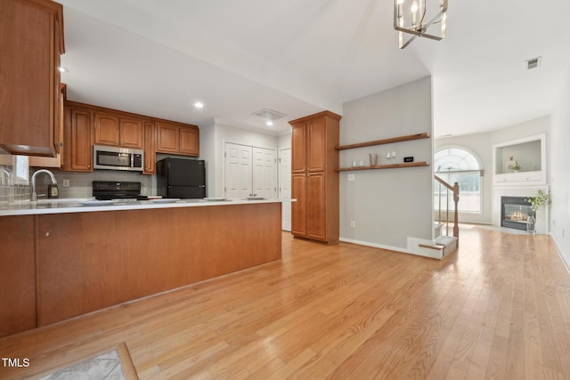 kitchen with sink, black appliances, light hardwood / wood-style flooring, kitchen peninsula, and backsplash