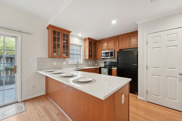 kitchen with sink, decorative backsplash, black appliances, and kitchen peninsula