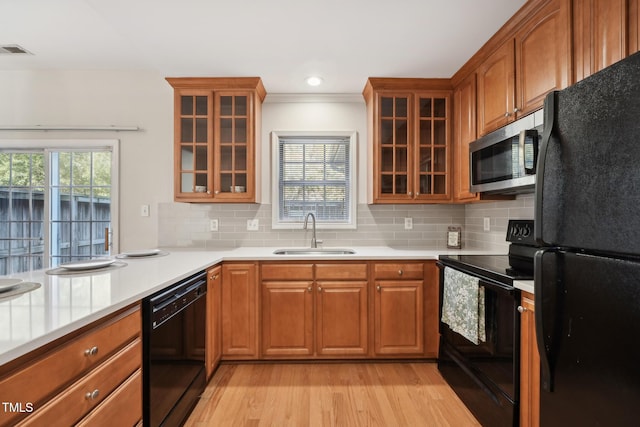 kitchen featuring sink, decorative backsplash, black appliances, and light wood-type flooring