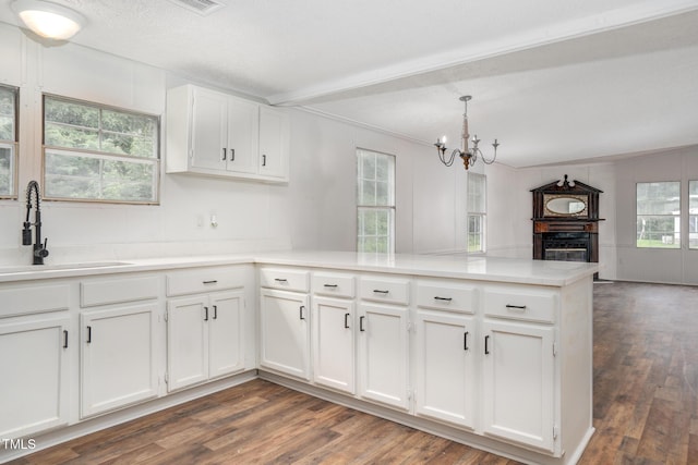 kitchen with pendant lighting, kitchen peninsula, sink, and white cabinets