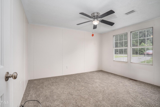 carpeted empty room with ceiling fan and a textured ceiling