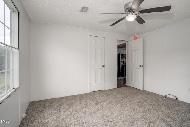 empty room featuring ceiling fan, carpet floors, and a textured ceiling