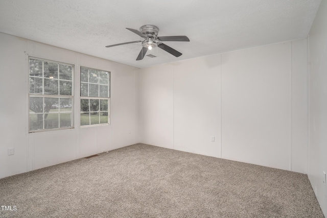 carpeted empty room with ceiling fan and a textured ceiling