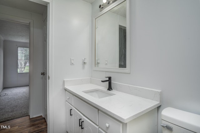 bathroom with hardwood / wood-style flooring, vanity, and toilet