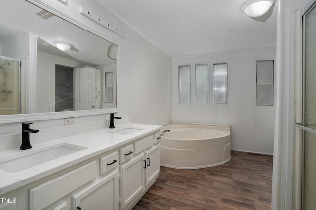 bathroom with independent shower and bath, vanity, hardwood / wood-style floors, and a textured ceiling