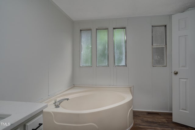 bathroom with vanity, a tub to relax in, and wood-type flooring