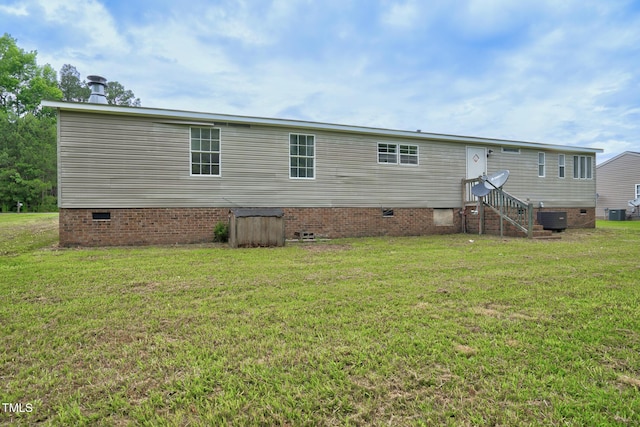 back of house with central AC unit and a lawn