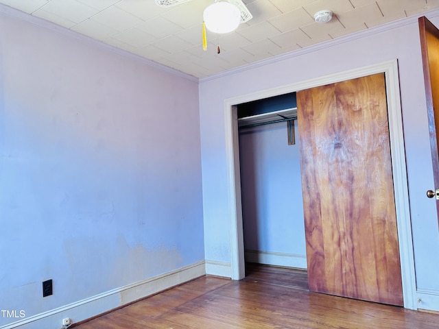 unfurnished bedroom featuring ornamental molding, dark hardwood / wood-style floors, and a closet