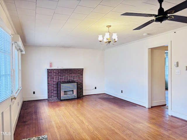 unfurnished living room with crown molding, hardwood / wood-style flooring, a fireplace, and ceiling fan with notable chandelier