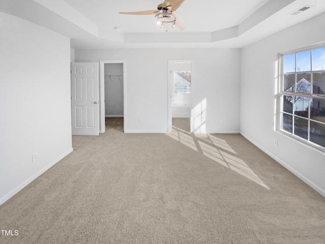 carpeted spare room featuring ceiling fan and a raised ceiling