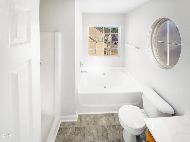 bathroom featuring a tub to relax in, toilet, and vanity