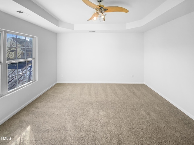 carpeted empty room featuring ceiling fan and a tray ceiling