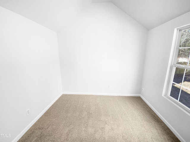 carpeted empty room featuring vaulted ceiling