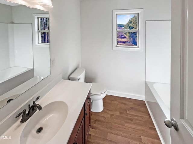 bathroom featuring vanity, hardwood / wood-style floors, a bathing tub, and toilet