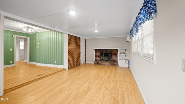 unfurnished living room featuring a fireplace, crown molding, wood-type flooring, and a wall unit AC