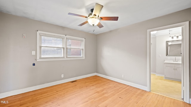 unfurnished bedroom featuring ceiling fan, ensuite bathroom, sink, and light wood-type flooring