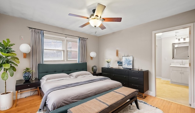 bedroom featuring ceiling fan, ensuite bathroom, sink, and light hardwood / wood-style flooring