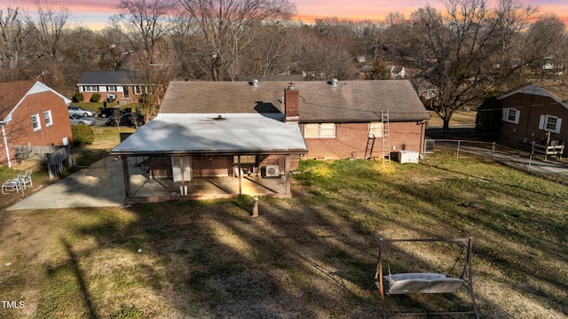 back house at dusk with a yard and a patio area