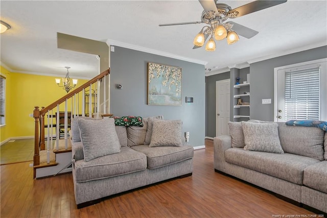 living room featuring wood-type flooring, ceiling fan with notable chandelier, and crown molding