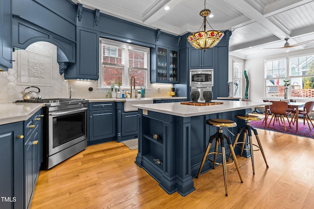 kitchen featuring pendant lighting, sink, blue cabinetry, stainless steel appliances, and a center island