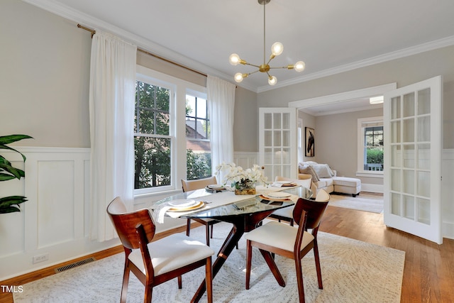 dining space featuring ornamental molding, hardwood / wood-style floors, an inviting chandelier, and french doors