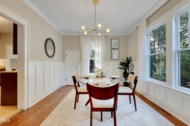 dining space with ornamental molding, plenty of natural light, an inviting chandelier, and light hardwood / wood-style flooring