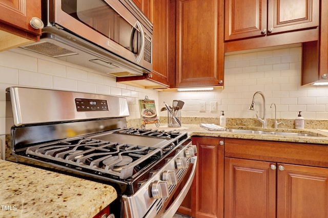 kitchen featuring light stone counters, appliances with stainless steel finishes, and sink