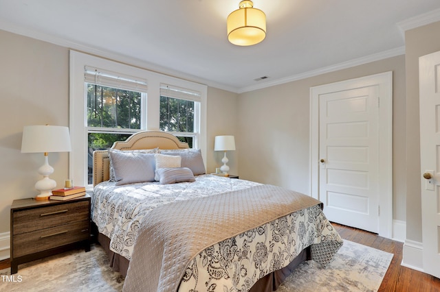 bedroom with ornamental molding and hardwood / wood-style floors