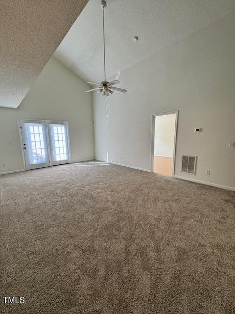 empty room with ceiling fan, high vaulted ceiling, carpet, and a textured ceiling