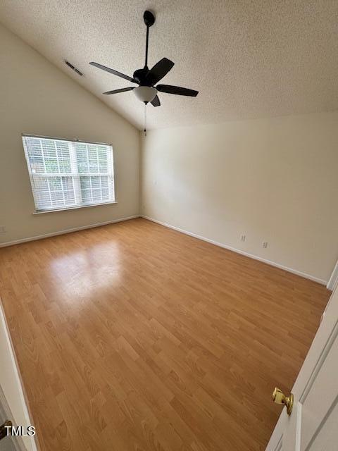 unfurnished room with lofted ceiling, a textured ceiling, ceiling fan, and light wood-type flooring