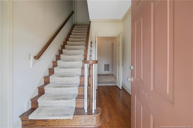 stairway with wood-type flooring and ornamental molding