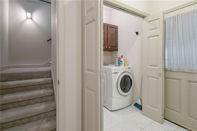 laundry area featuring washer / dryer, cabinets, and light tile patterned flooring