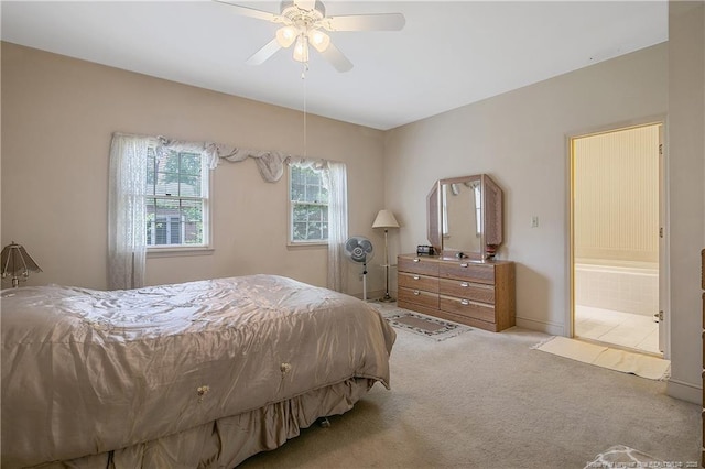 bedroom with ceiling fan, light colored carpet, and ensuite bathroom