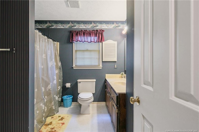 bathroom featuring tile patterned flooring, vanity, a textured ceiling, and toilet