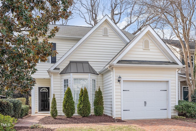 view of front of house with an attached garage, decorative driveway, and roof with shingles