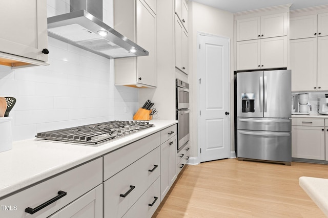 kitchen featuring appliances with stainless steel finishes, extractor fan, light hardwood / wood-style flooring, and white cabinets