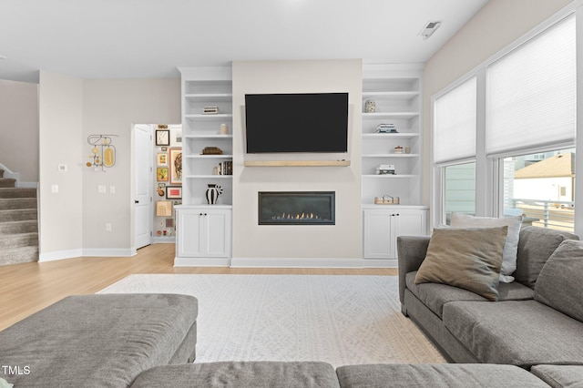 living room featuring built in shelves and light hardwood / wood-style floors