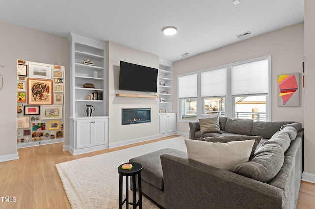 living room featuring built in shelves and light wood-type flooring