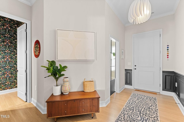 foyer entrance with crown molding and light wood-type flooring