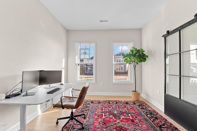 office with a barn door and light wood-type flooring