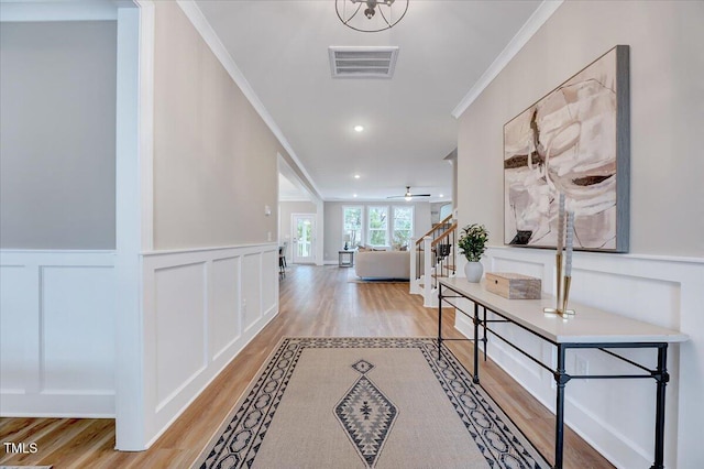 hall with ornamental molding and light wood-type flooring